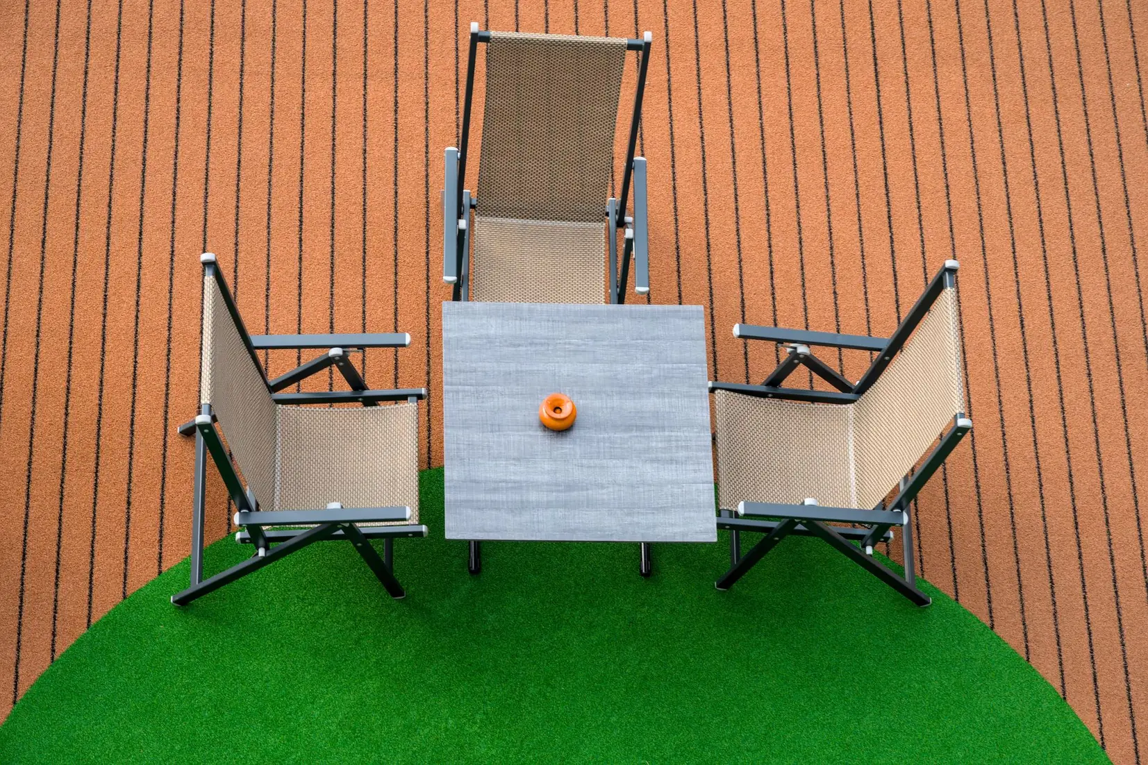 Outdoor table and chairs arranged on artificial turf beside a wood deck