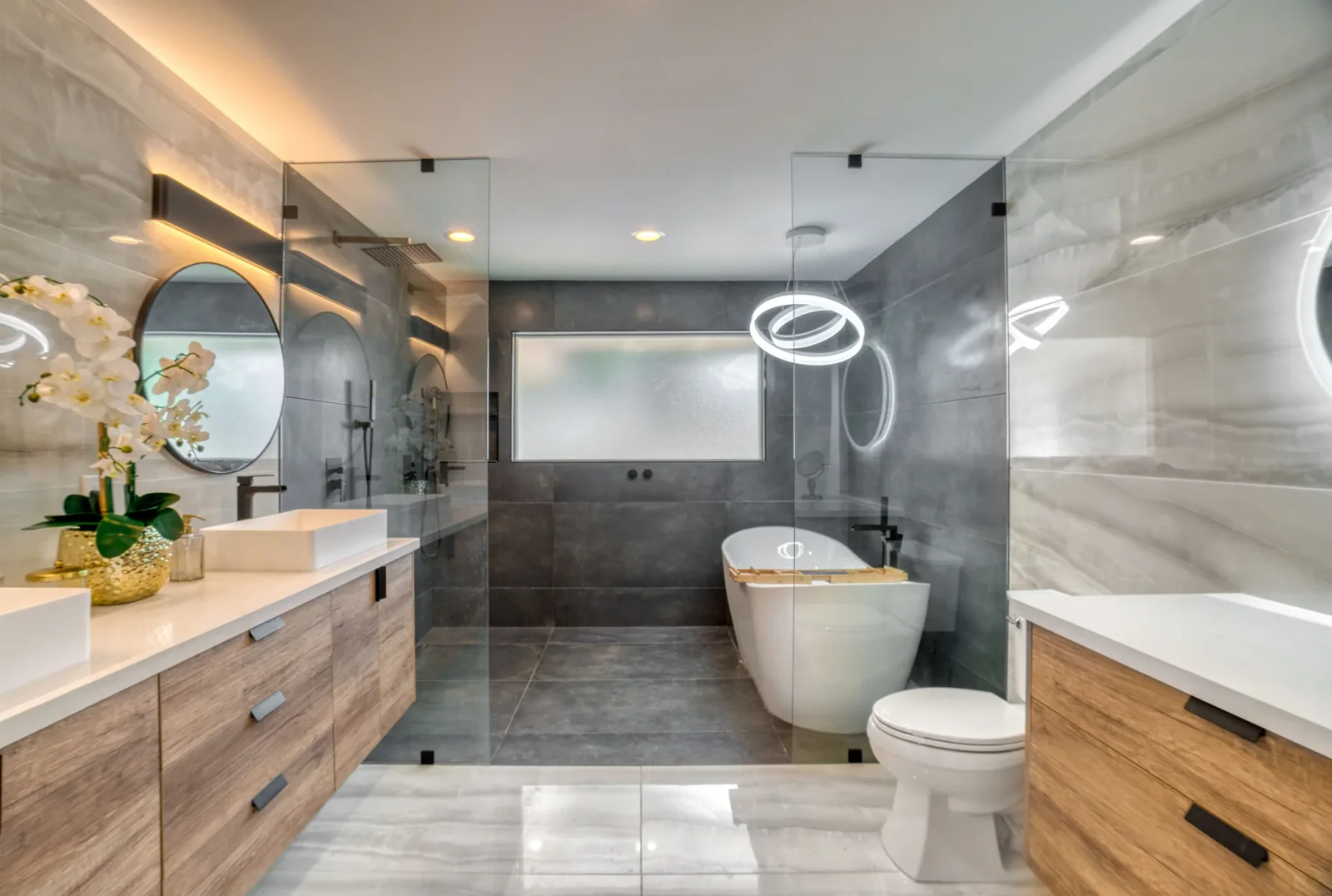 Bathroom with a freestanding tub between a double vanity and a glass enclosed shower