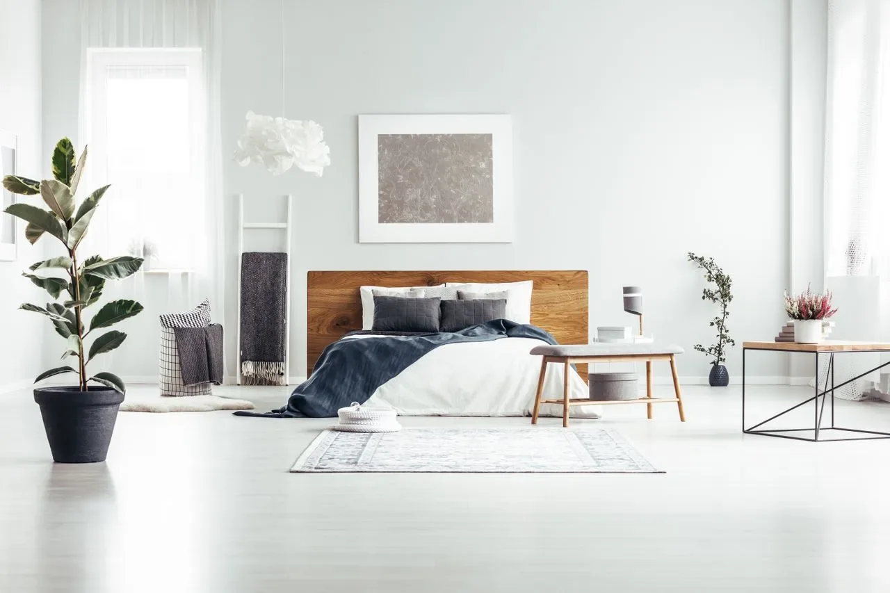 Minimal bedroom in white and pale timber with a framed print above the headboard