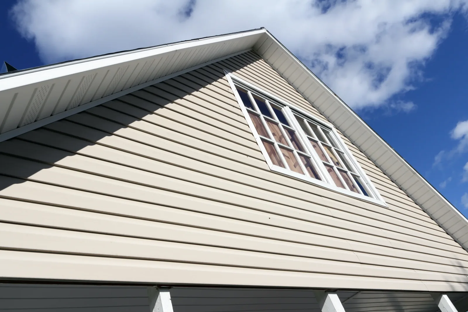 Gable end of a home clad in horizontal siding with a row of windows below the roofline