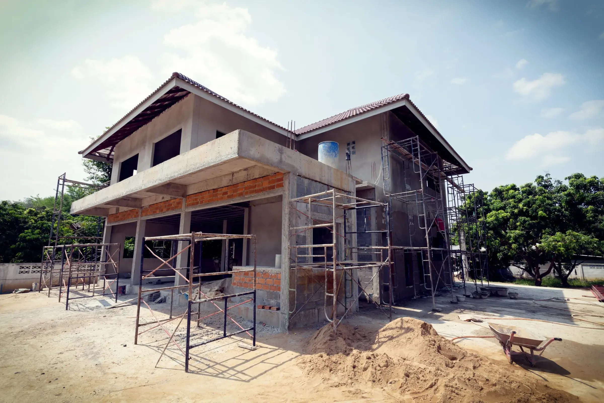Scaffolding around a two-story house with the stucco coat going on