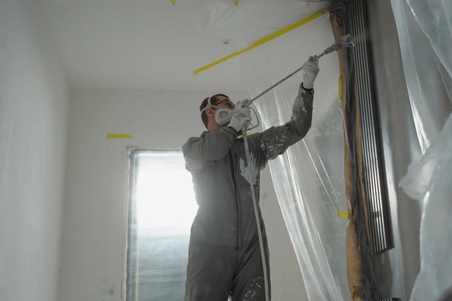 Painter working carefully along an interior wall with floors and openings protected