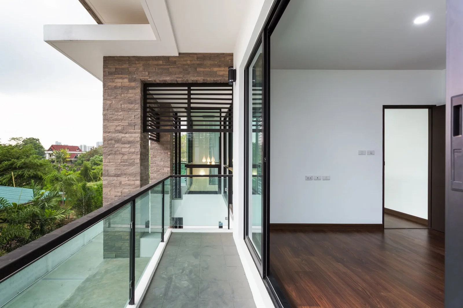 Empty room opening onto a balcony through a full height sliding glass door