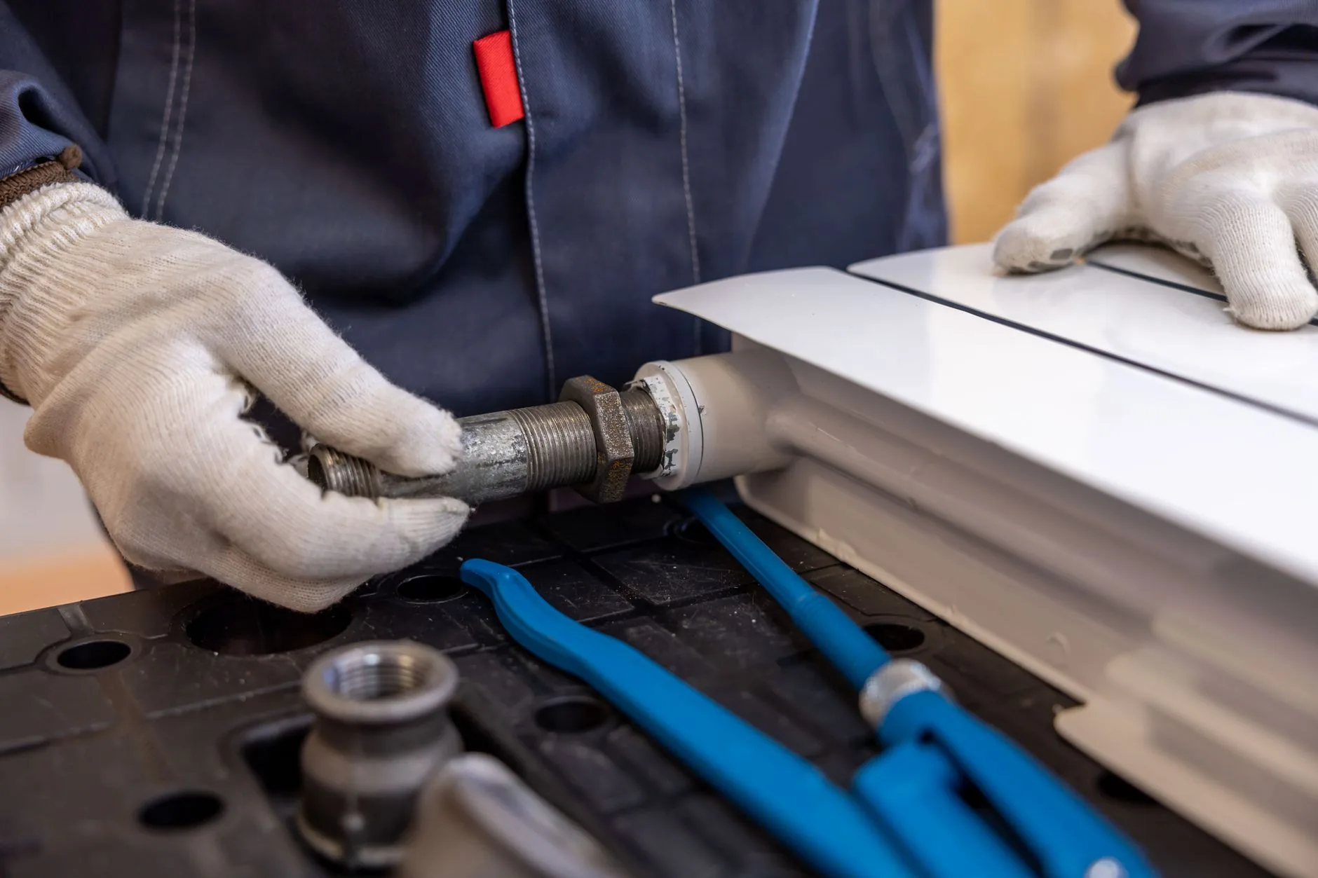 Gloved technician connecting a threaded plumbing fitting to equipment
