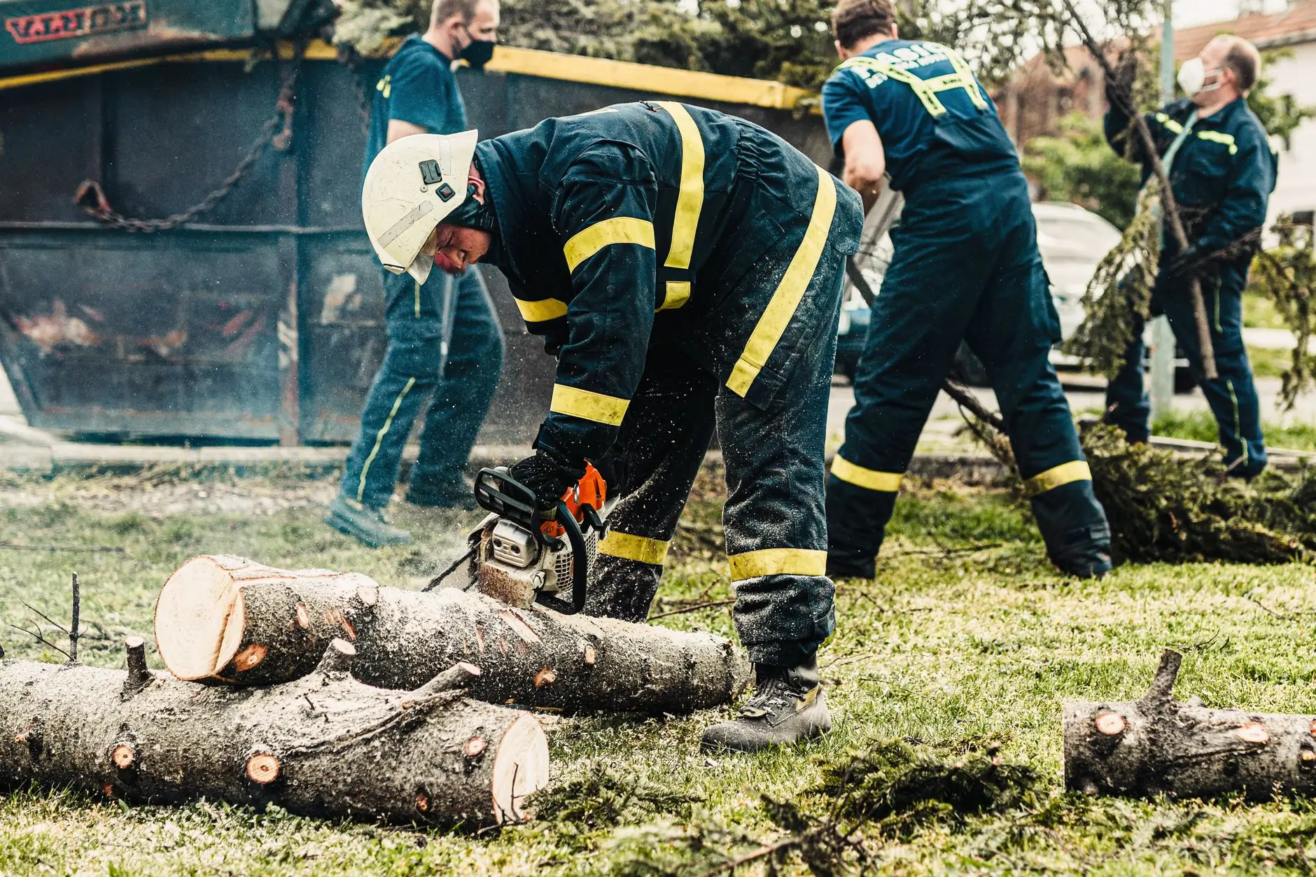 Tree crew cutting and clearing large branches at ground level